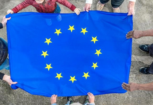 Viele Hände halten die EU-Flagge wie ein Sprungtuch fest